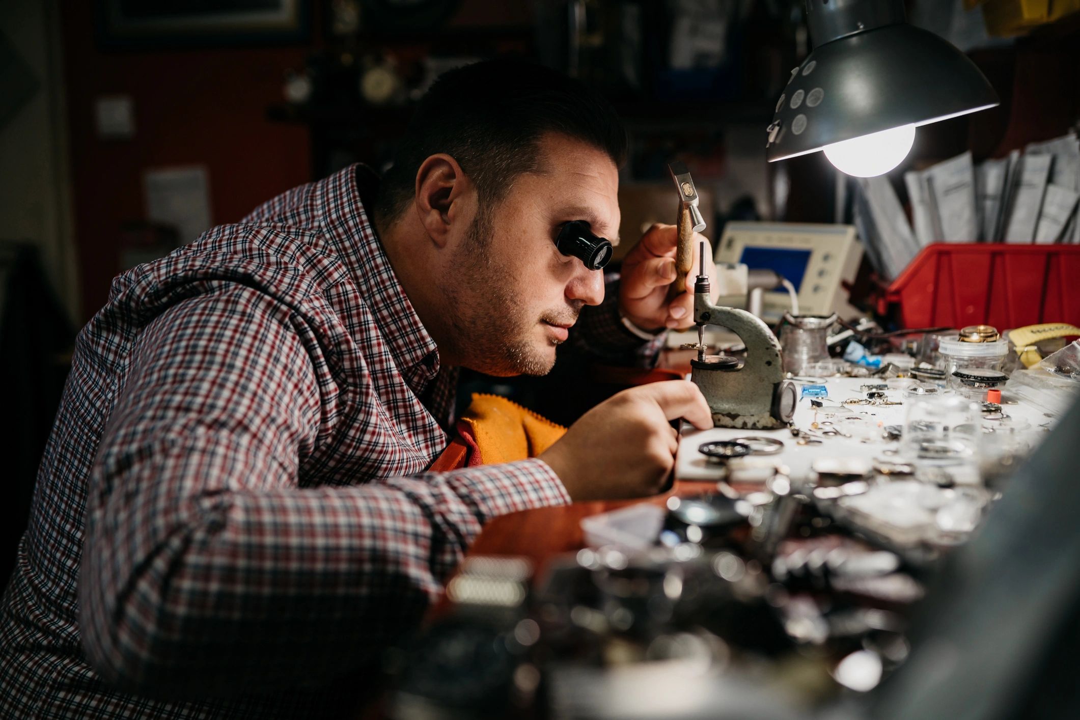 Watchmaker hands working on a mechanical watch at a workbench